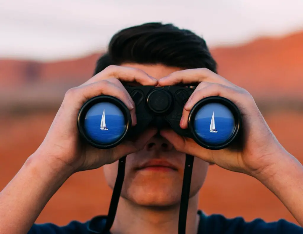 Man looking through binoculars towards camera